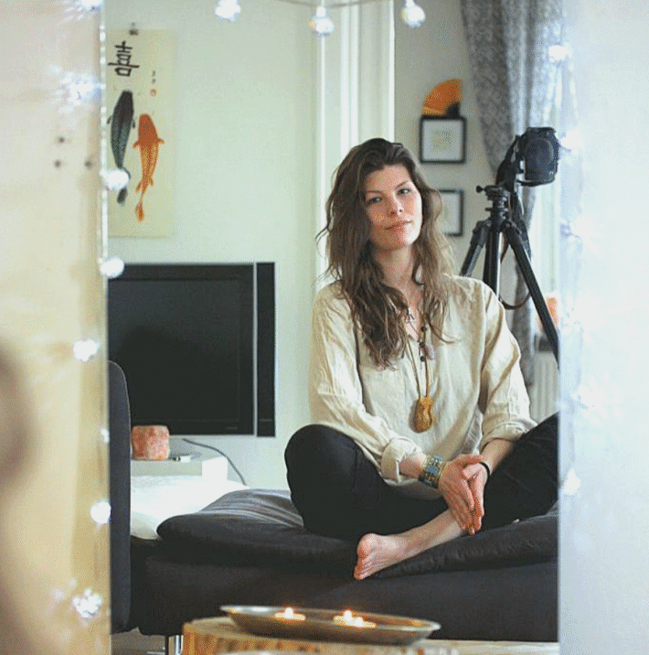 Foto på kvinna i svarta byxor och korslagda ben, hon heter Karolina Eleonora och ger healing.