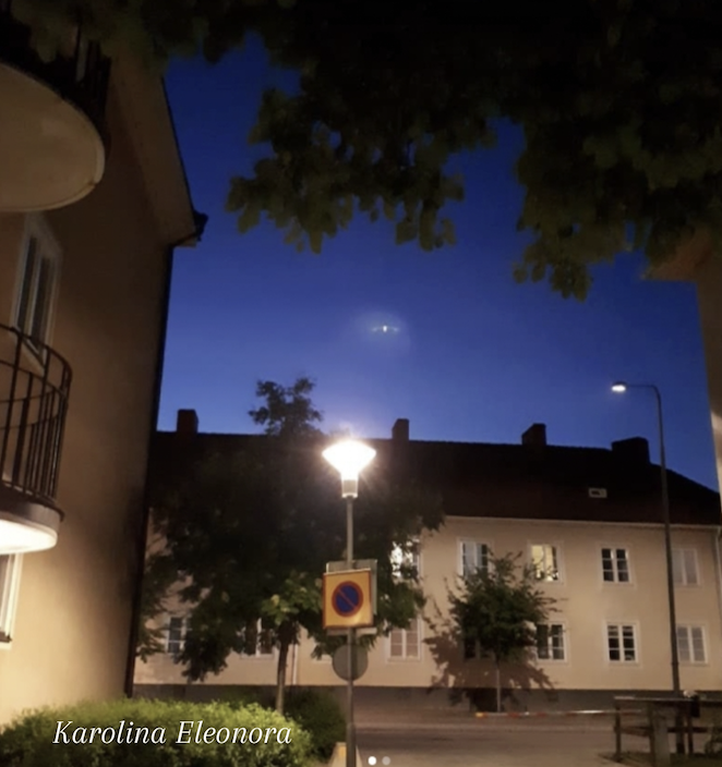 Bostadsområde med ett 7D Pleiadian skepp som fotats emot blå kvällshimmel
