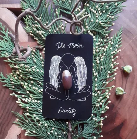 Gröna kvistar med ett svart orakelkort på ett bord, en Tidigare Liv healingbehanling av Karolina Eleonora