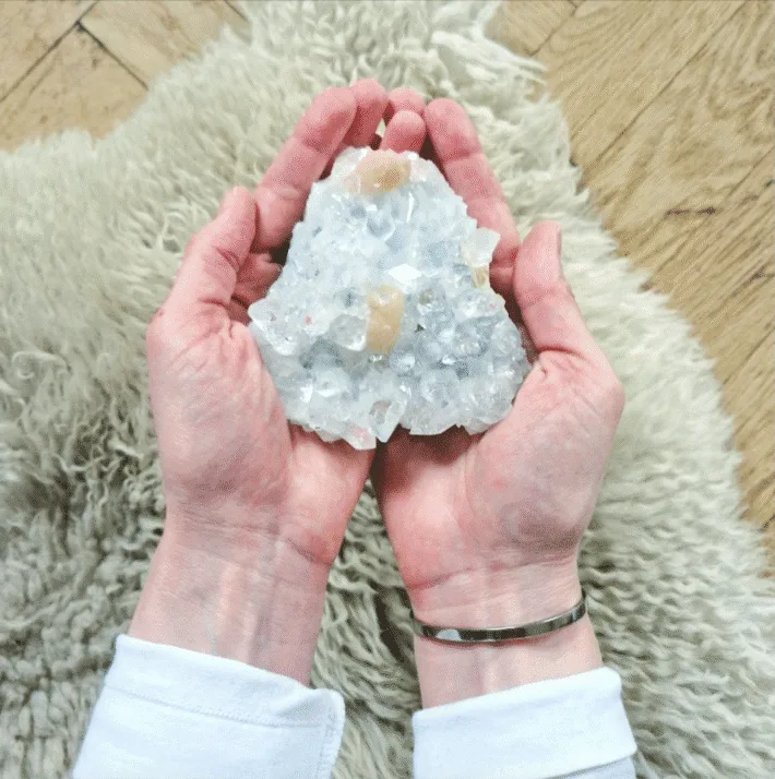 Två händer håller en kristall över ett fårskinn. En symbol för Själsvila Paketet, Karolina Eleonoras healing.